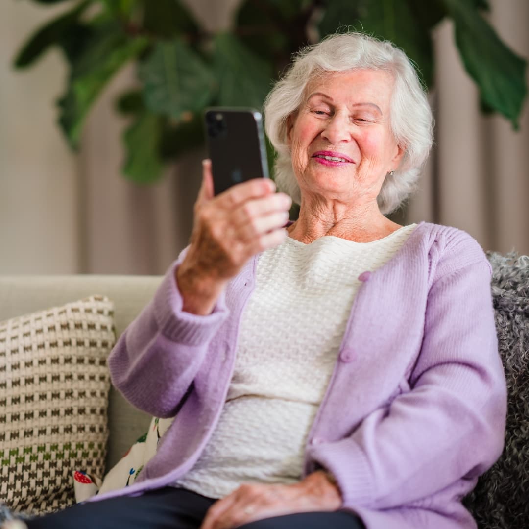 Elderly woman smiling at her mobile phone