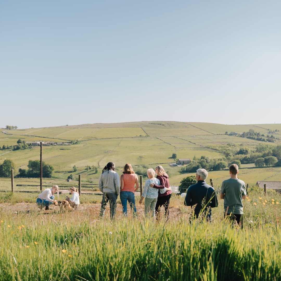 Client, Care Professional and their family walking through a sunny field