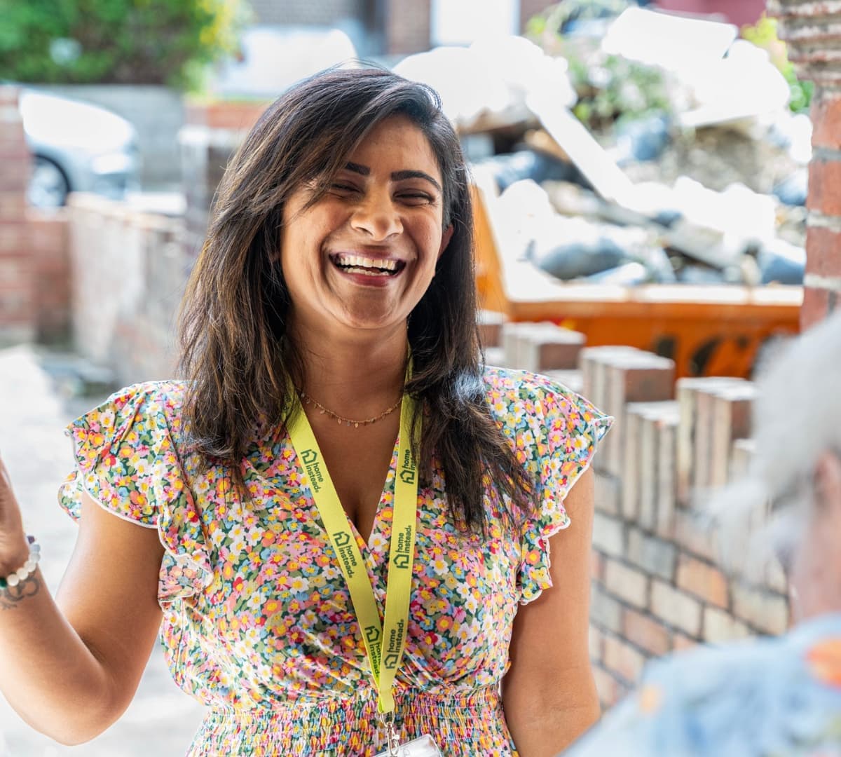 A woman with long black hair happy and smiling while being greeted at the door