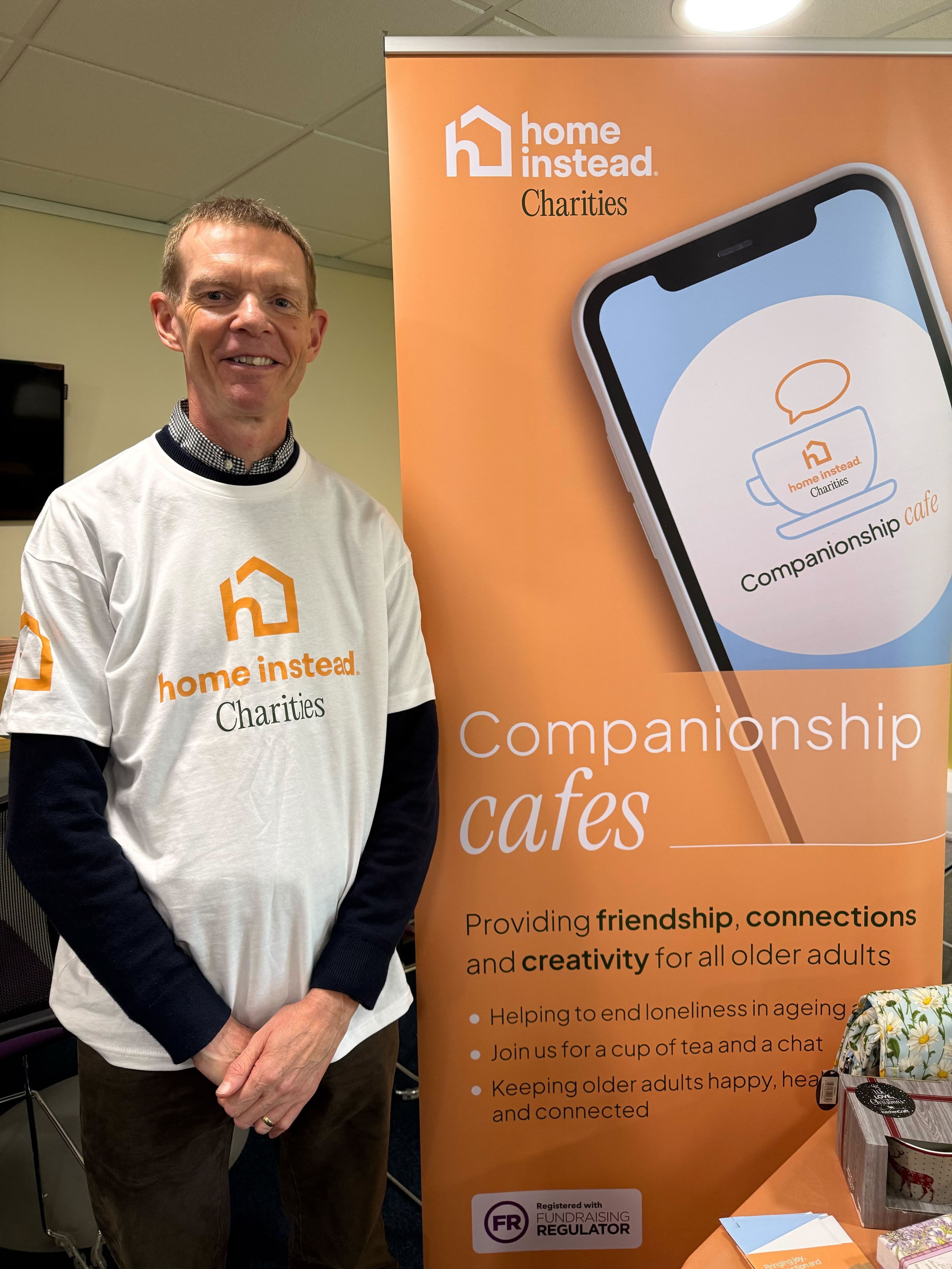smiling man next to a Home Instead charities banner