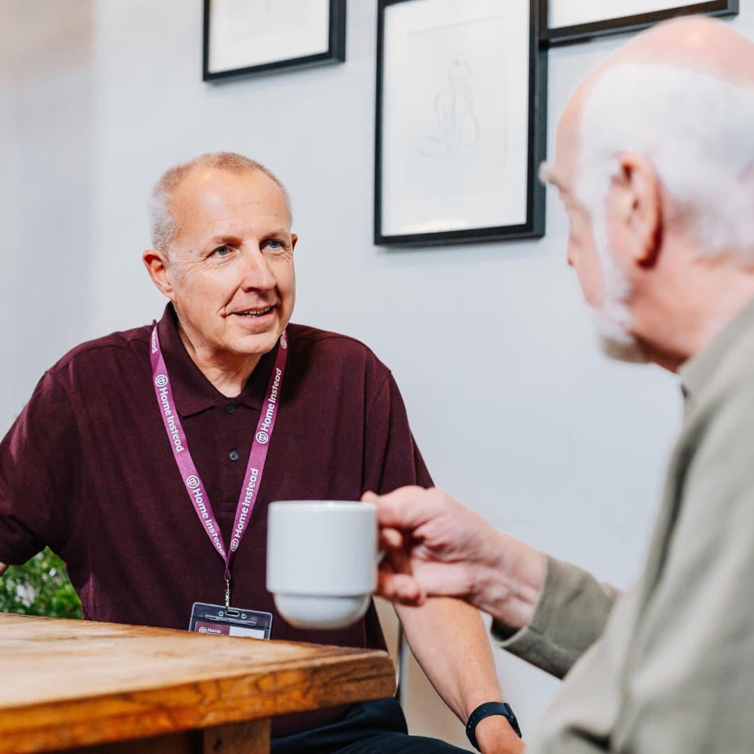 Male Client and Care Professional chatting at the table with a cup of tea