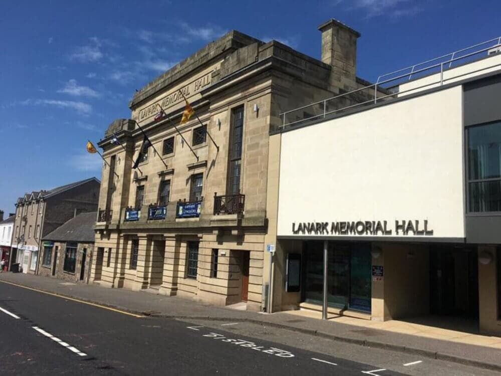 Front view of Lanark Memorial Hall, a historical building with a modern extension, on a sunny day. - Home Instead