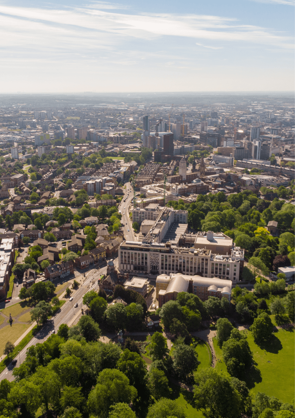 Aerial view of a cityscape with buildings, green spaces, and tree-lined roads on a clear day. - Home Instead