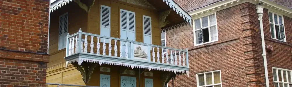 A brick and wood house with ornate details, featuring a balcony with white railings and decorative trim. - Home Instead