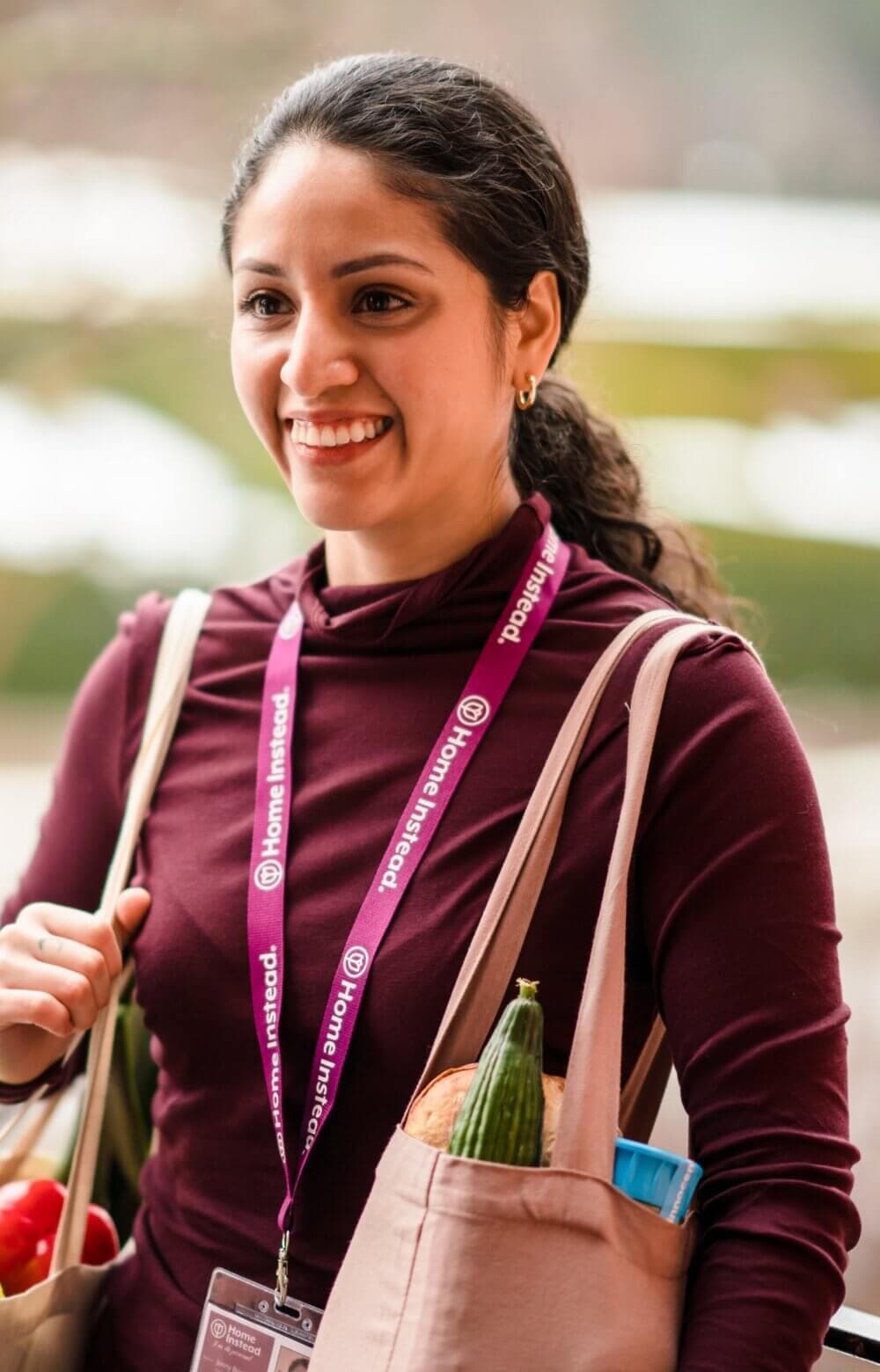 An elderly man and a caregiver smiling in a cozy kitchen with a cup of coffee on the table. - Home Instead