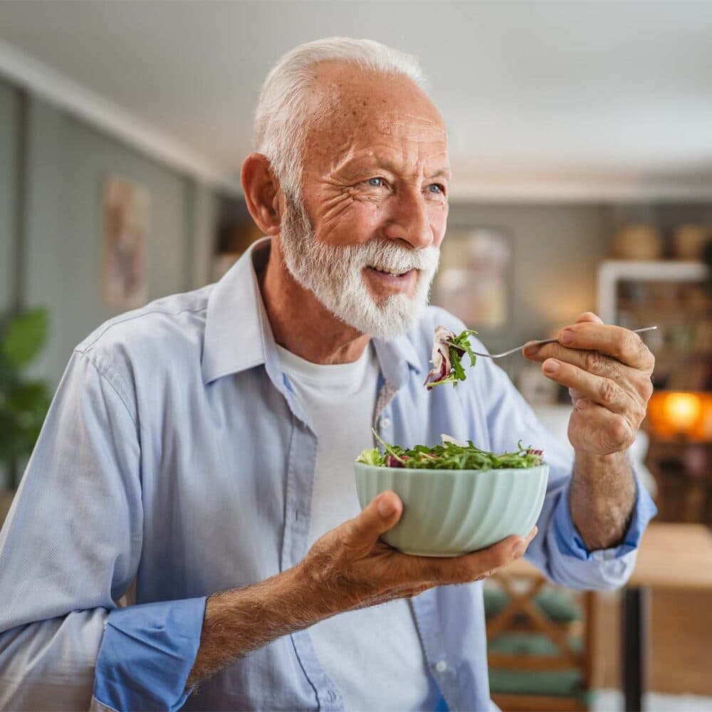 elderly man eating a healthy salad meal to support balanced diet