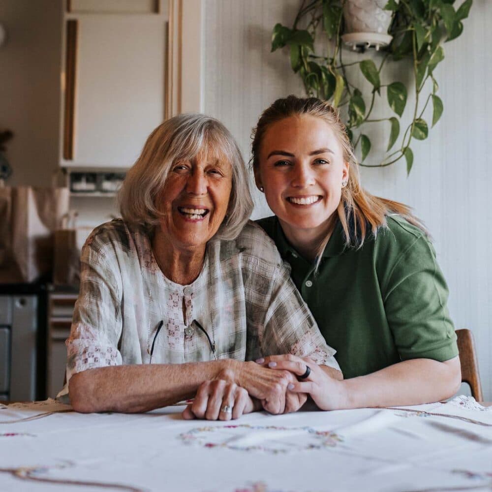 Home Instead Ascot care professional sitting next to her client smiling