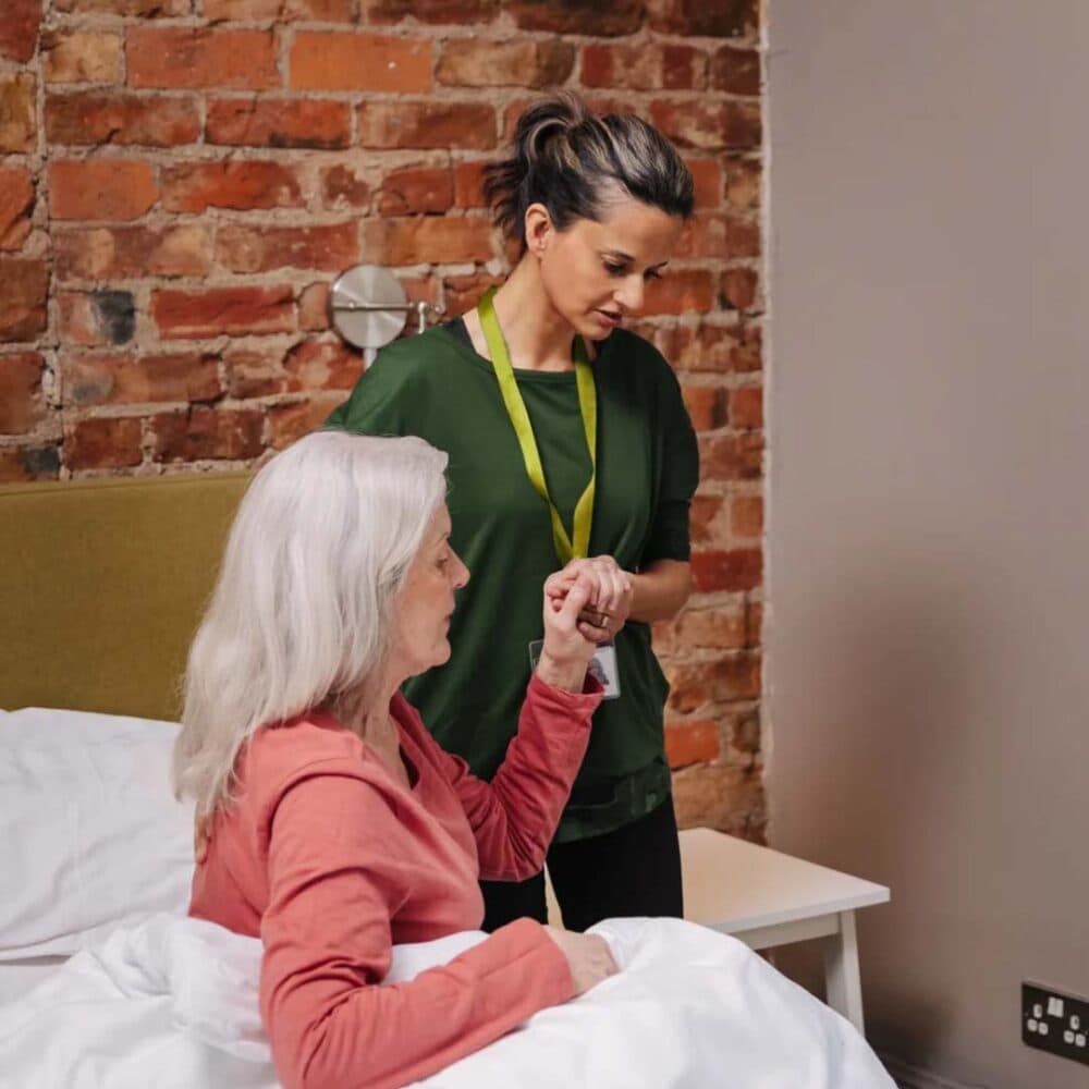 Home Instead care professional supporting client out of bed
