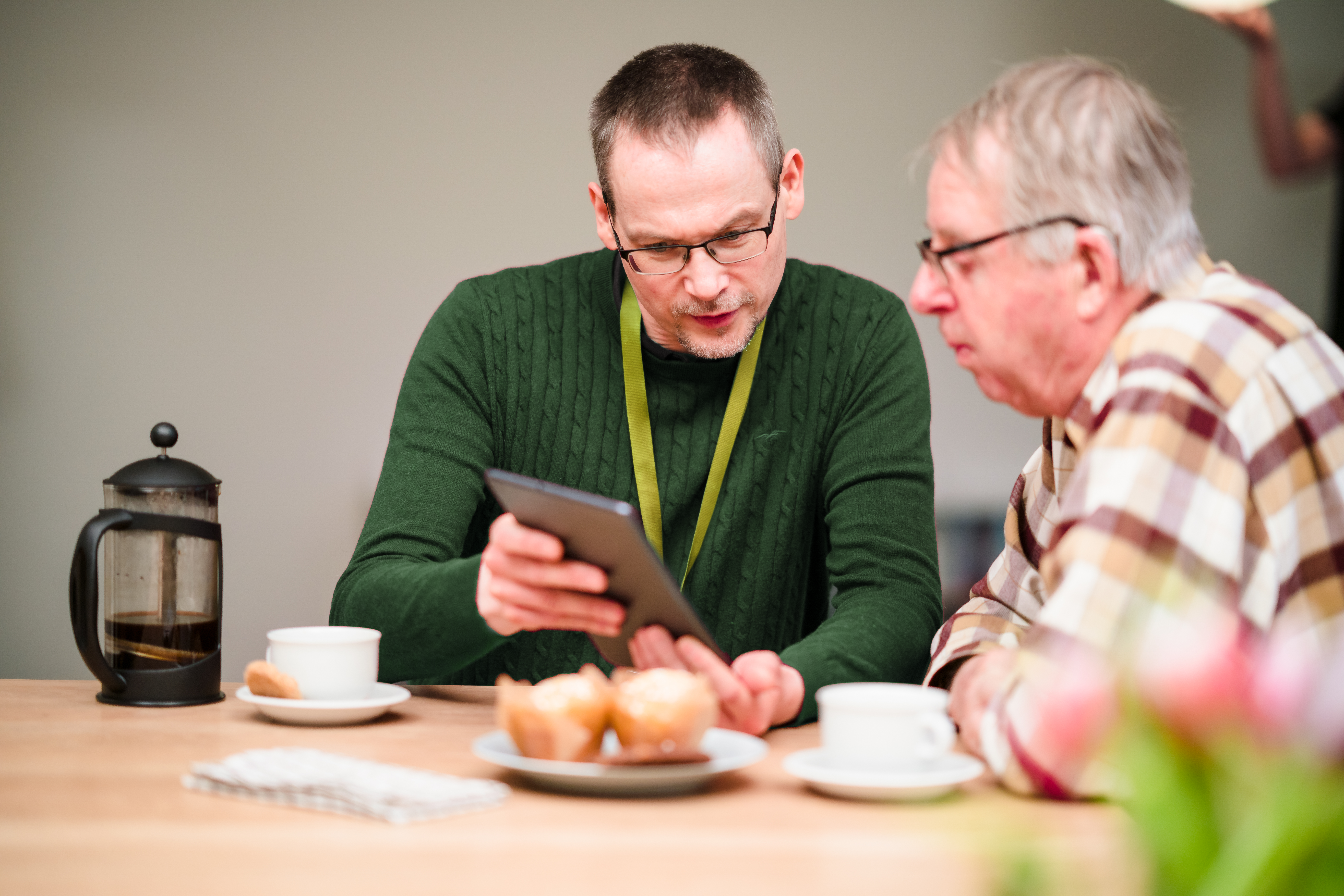 Male Care Professional looking at tablet with senior man - Home Instead