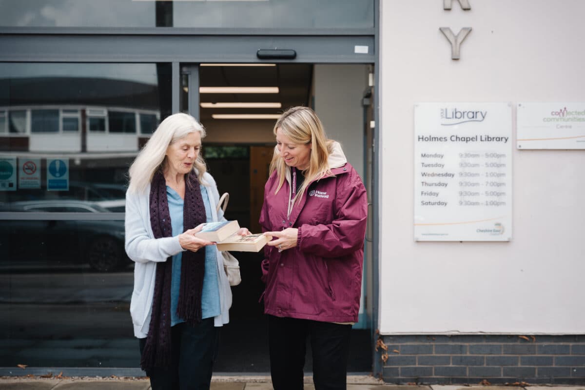Female care pro and female client coming out of a library, companionship care