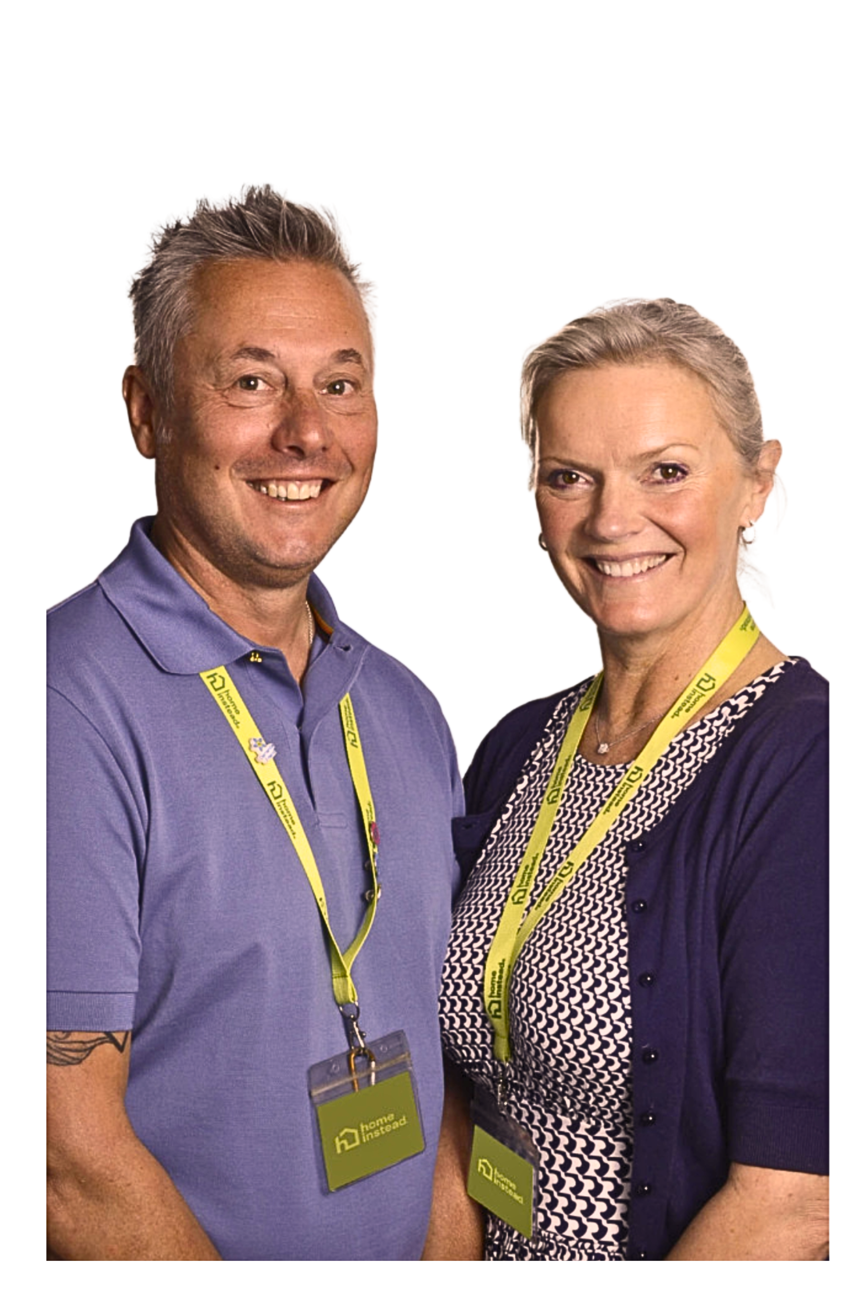 A smiling woman with short gray hair stands next to a smiling man with short gray hair in front of a purple background. - Home Instead