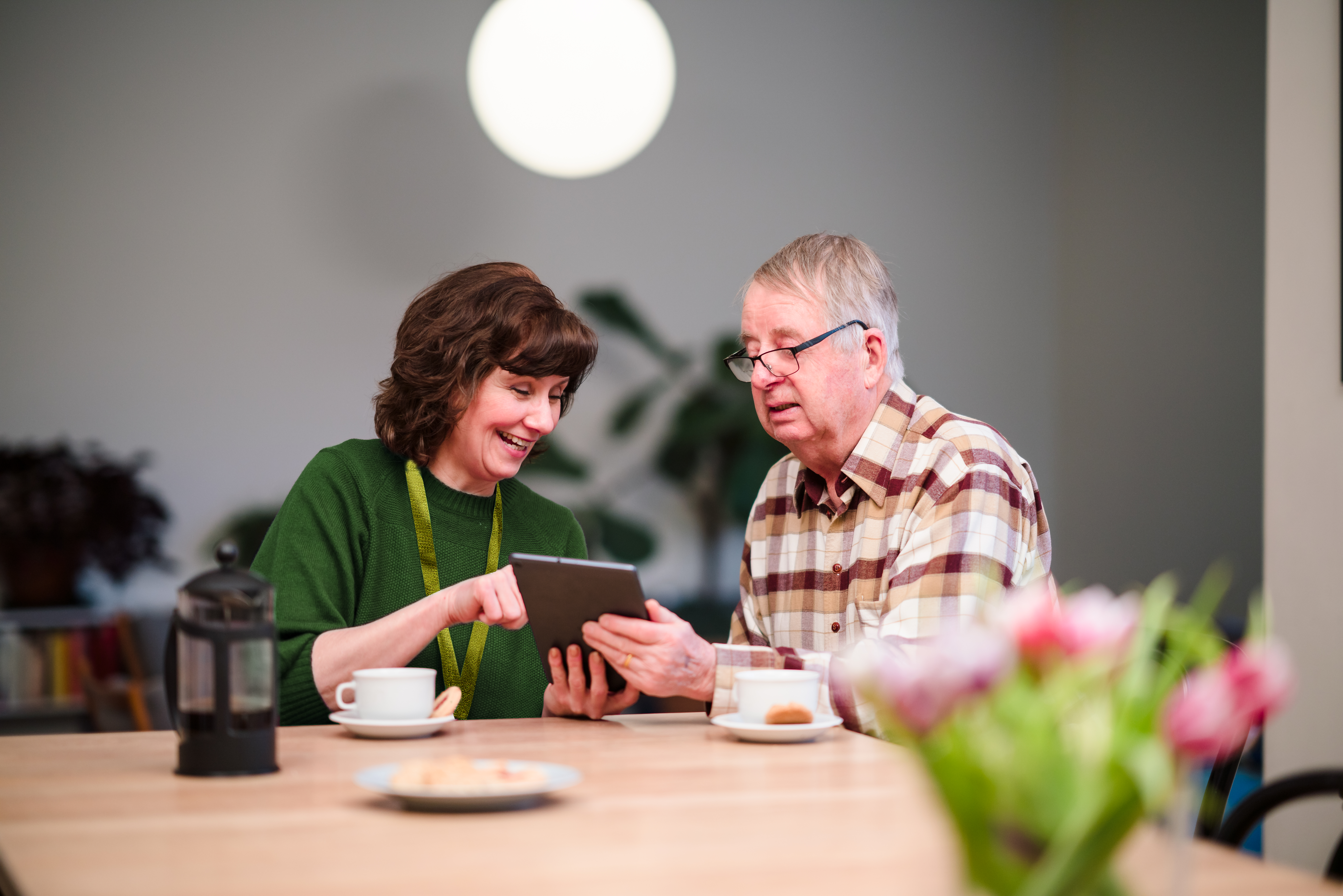 female care pro teaching a male client to use a tablet